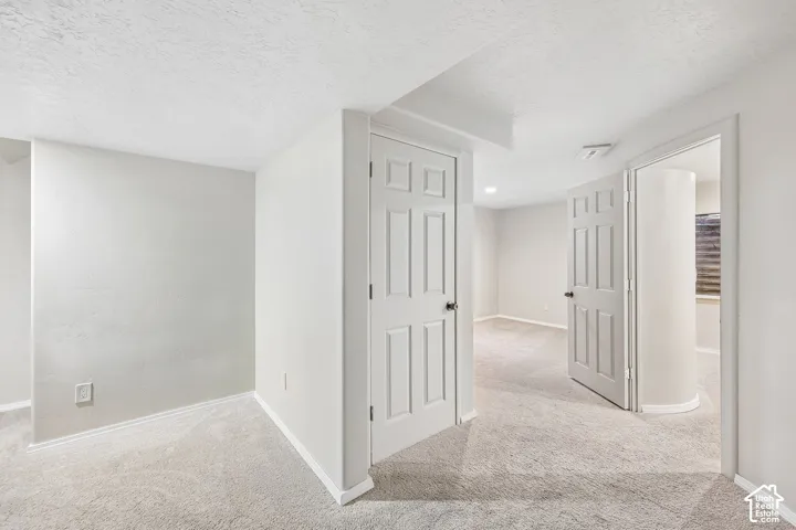 Neutral tone wall paint, textured ceiling, light-toned carpet flooring, white paneled doors, and recessed lighting
