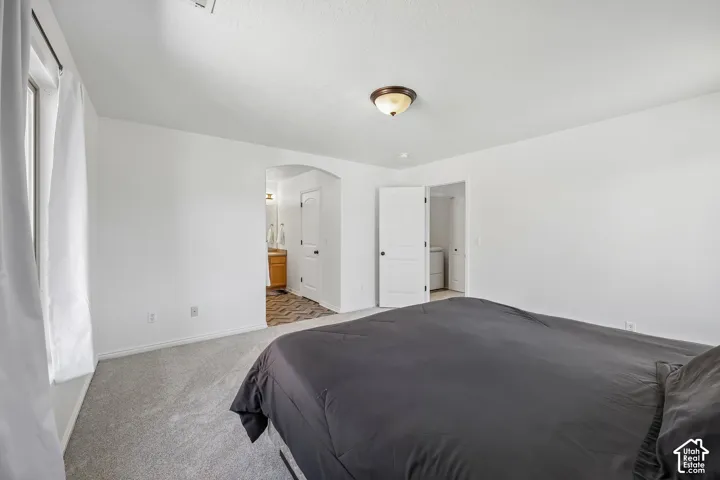 Light-colored carpeting, white walls, and a window with white curtains