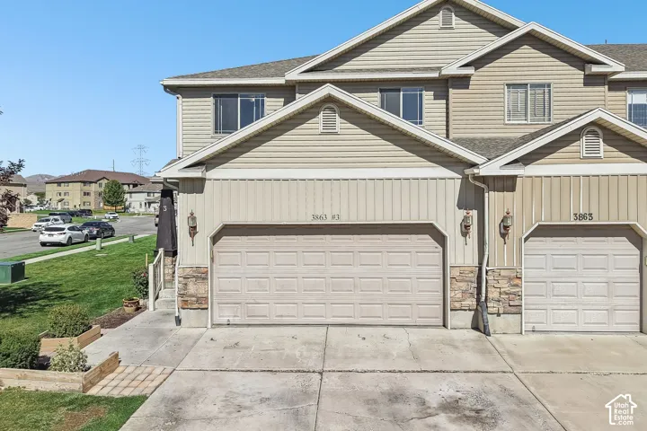 Neutral-toned siding exterior with stone veneer accents, individual garage doors, and upper-level windows