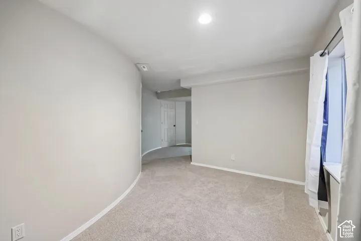 Neutral-toned carpeting, recessed ceiling lighting, and a window with a white sill