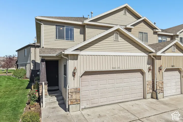 Two-story exterior with light-toned siding, attached garage, stone accents, and a covered entry