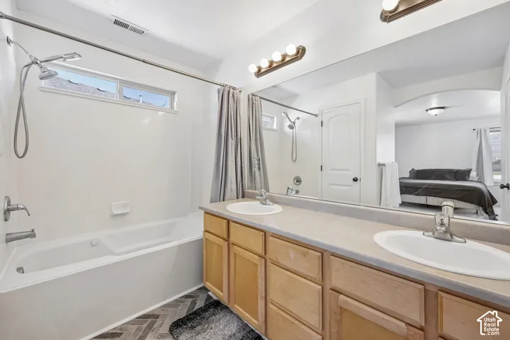 Double vanity with integrated sinks, light wood-finish cabinetry, and a large wall-mounted mirror