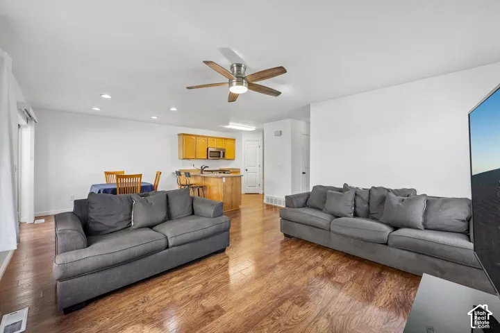 Open-concept living area with wood-finish flooring, recessed lighting, and a ceiling fan