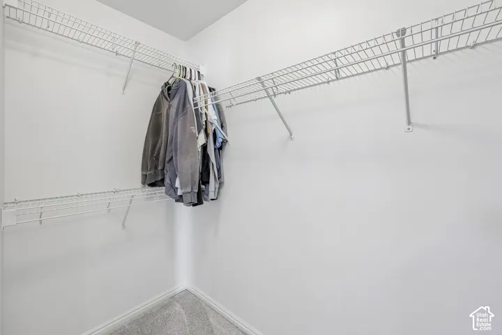 Wall-mounted wire shelving system with hanging rods in a white-walled interior