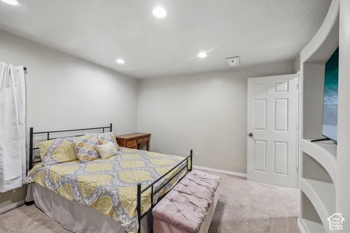 Recessed ceiling lighting, light-toned wall paint, neutral carpet flooring, and a built-in shelving unit