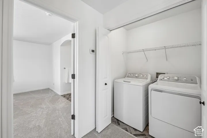 Dedicated laundry area with wire shelving, herringbone-patterned flooring, and a nearby arched entryway