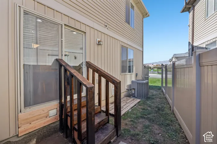 Sliding glass door access, exterior stairs with wood railing, horizontal siding, and a privacy fence