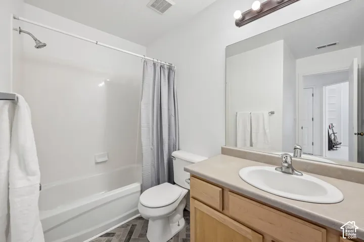 Bathroom featuring a shower-tub combination, vanity with an integrated sink, broad wall mirror, and wood-finish flooring