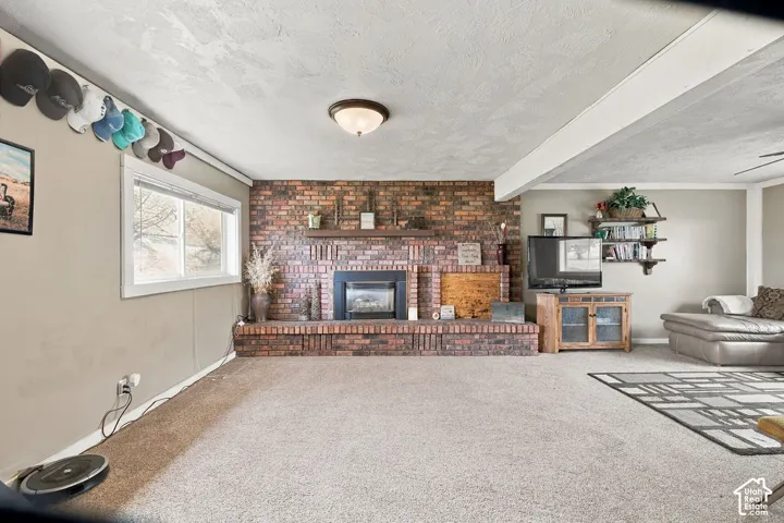 Expansive room featuring a brick-surround fireplace, wood mantel, and a dedicated window
