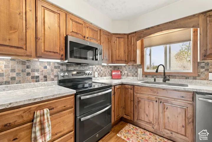 Wood cabinetry with integrated appliances, mosaic tile backsplash, and light-toned countertops