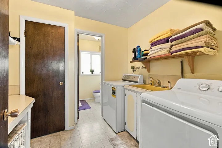 Laundry area featuring vinyl flooring, a utility sink, and a wall-mounted storage shelf