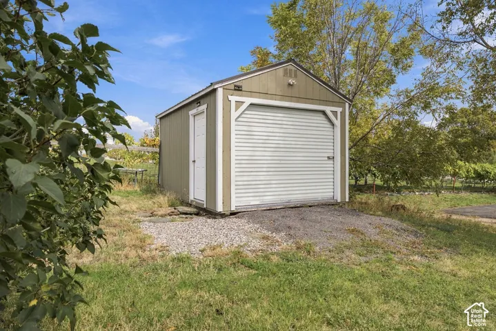 Detached shed with overhead garage door, single entry door, and gravel apron