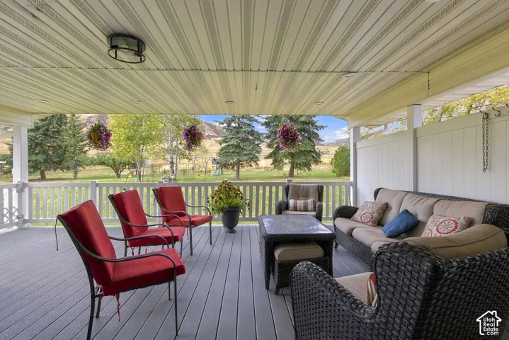 Covered patio with a composite deck, white railing, slatted ceiling, and wall-mounted light fixture