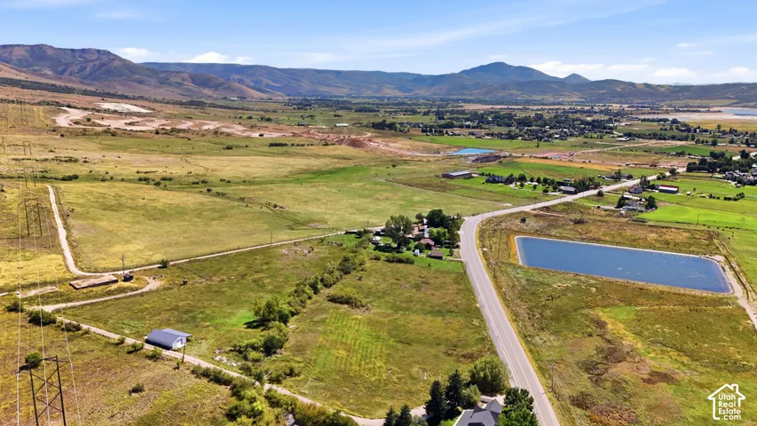 Expansive land parcel featuring open fields, a paved road, and a large water reservoir