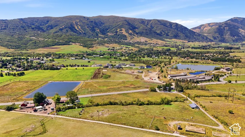 Expansive property featuring mountainous terrain, multiple natural bodies of water, and an array of agricultural structures