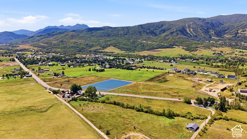 Expansive rural landscape featuring a large body of water, surrounded by green fields and distant mountains