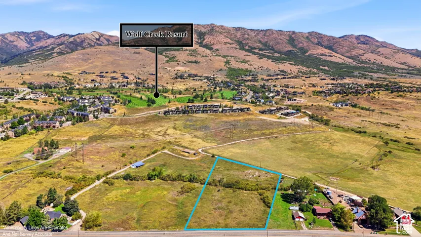 Expansive land parcel with surrounding mountain terrain, bordered by paved roadway, and featuring varied green and brown foliage