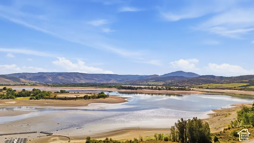 Expansive body of water with surrounding natural landscape, distant mountains, and clear blue sky