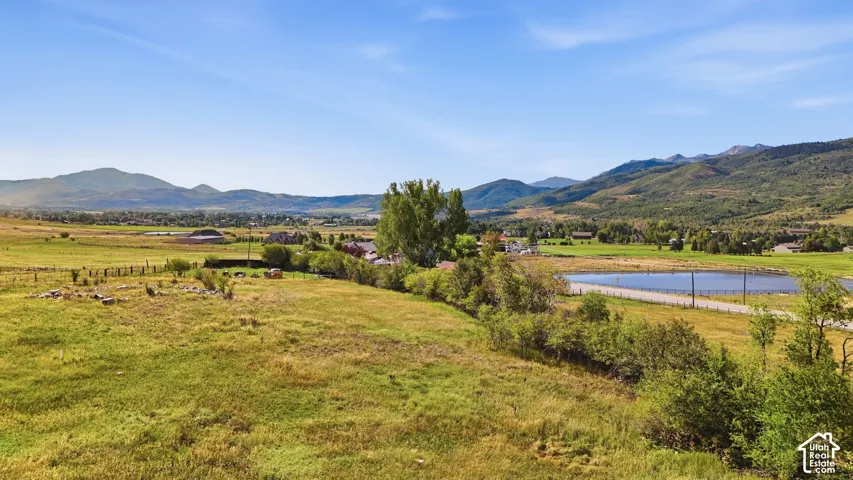 Expansive landscape featuring open fields, distant mountain ranges, and a visible body of water
