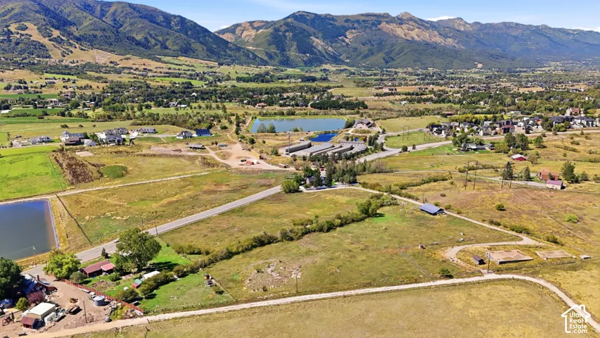 Expansive rural setting featuring a winding roadway, diverse vegetation, and distant mountain ranges