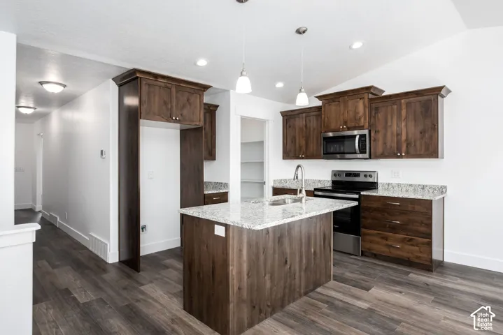 Kitchen featuring wood-finish flooring, dark wood cabinetry, granite countertops, and stainless steel appliances