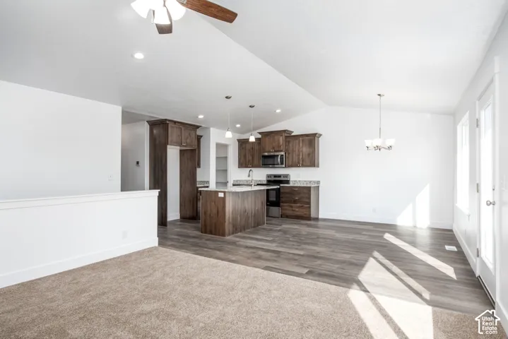 Bright open-concept kitchen with wood-finish flooring, recessed lighting, and a vaulted ceiling