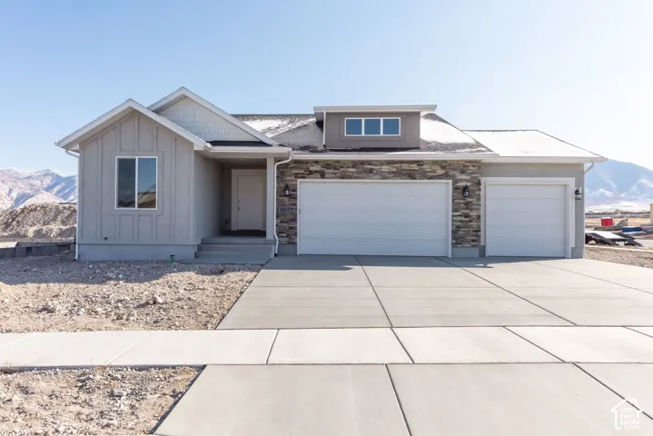 Contemporary exterior with board and batten siding, stone facade accents, a two-car garage, and a single-car garage