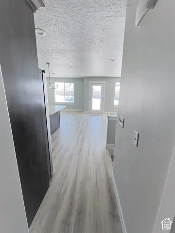 Wood-finish flooring throughout, light gray walls, white trim, recessed lighting, and a white exterior door