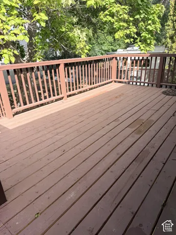 Expansive outdoor deck with wood railing and tree canopy backdrop