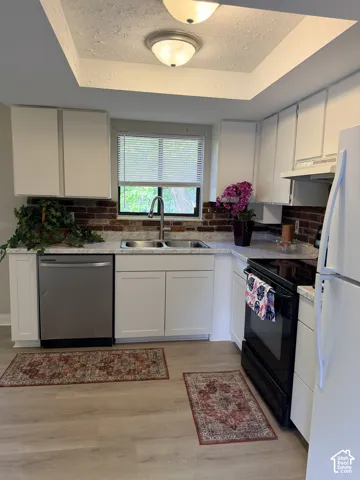 Kitchen featuring light wood-finish flooring, white cabinetry, a stainless steel dishwasher, and a double basin sink with a gooseneck faucet