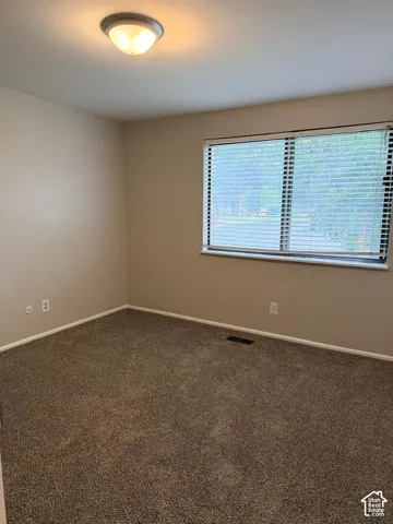 Neutral tone wall paint, flush mount ceiling light fixture, and window with blinds