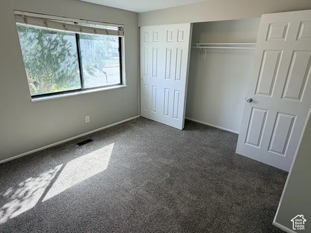 Neutral wall color, window with blinds, panel doors, and built-in closet shelving