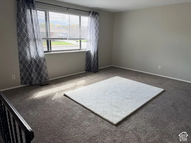 Carpeted flooring, neutral wall paint, and a large window with blinds