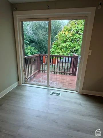 Sliding glass door opening to an exterior wood deck with a wood railing