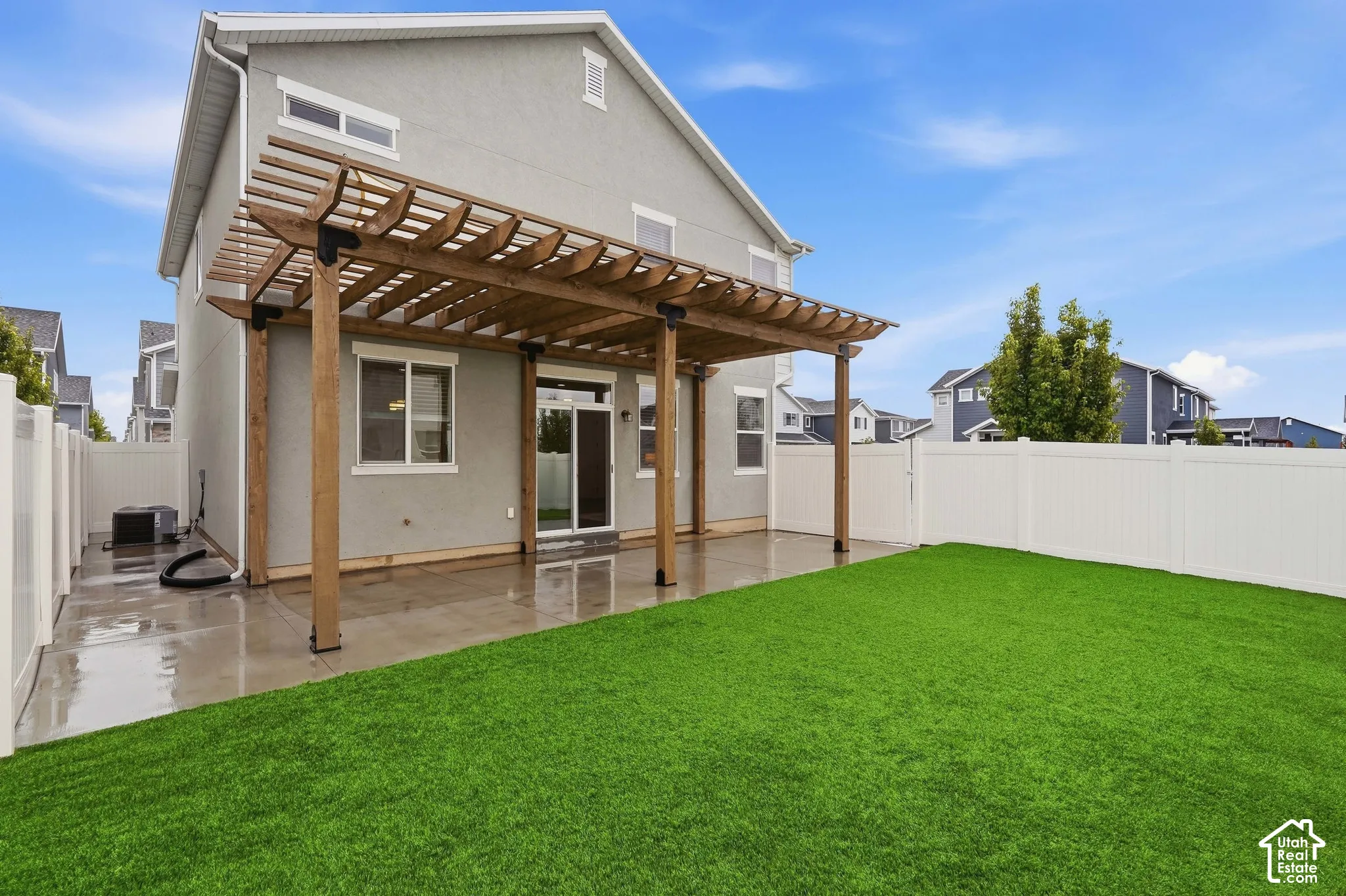 Expansive backyard with artificial turf, private vinyl fencing, a concrete patio, and a wood pergola