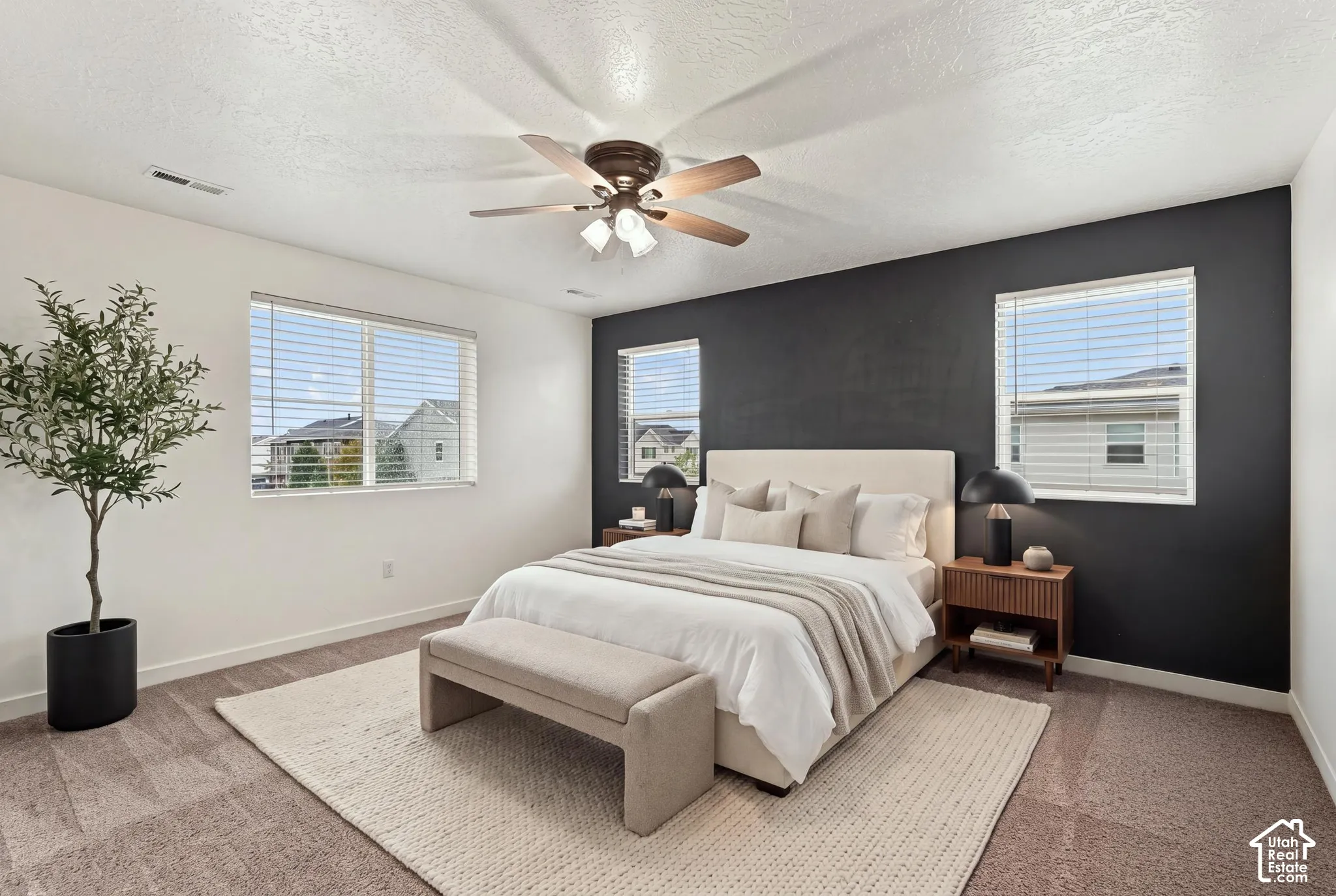 Recessed lighting, ceiling fan with integrated lighting, multiple windows with horizontal blinds, and accent wall