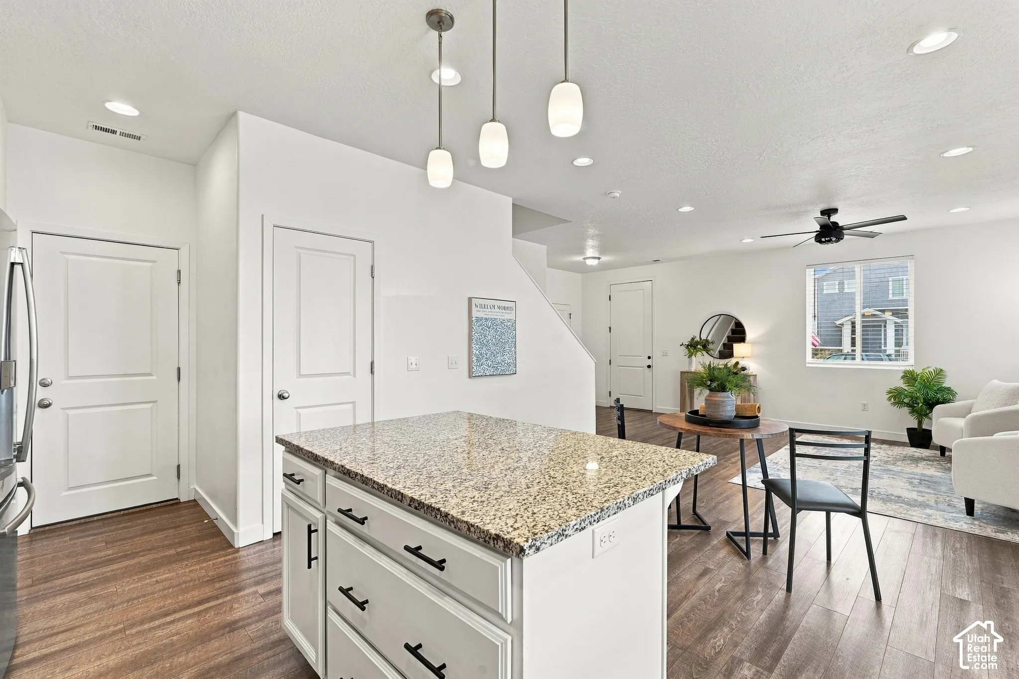 Kitchen island with a light granite countertop and pendant lighting