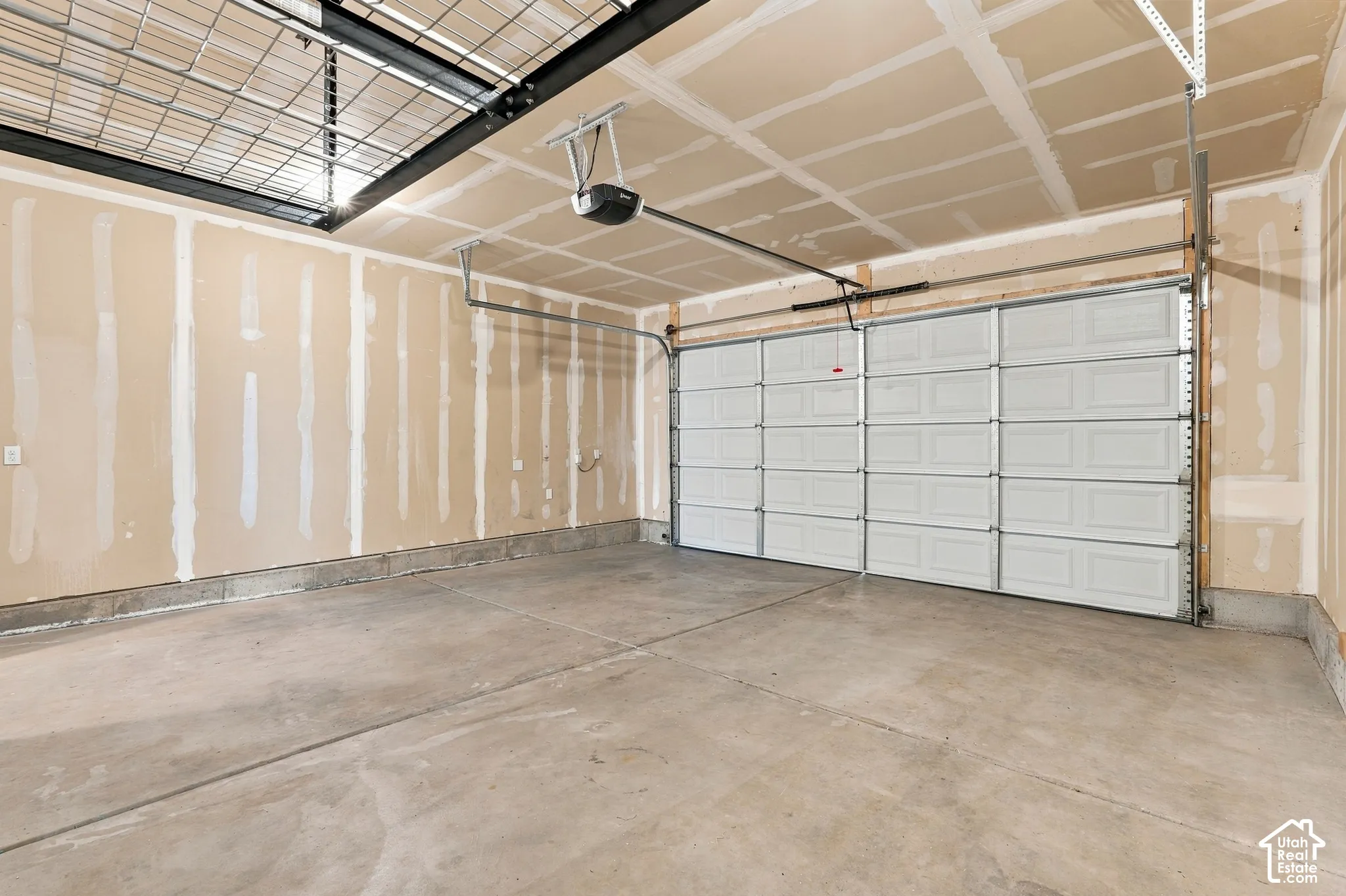 Spacious concrete floor garage featuring a paneled overhead door, an automatic garage door opener, and overhead wire storage shelving