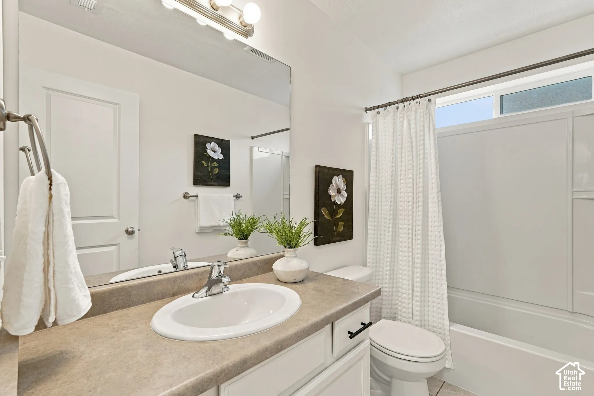 Bathroom featuring an integrated sink, vanity with cabinet storage, a large mirror, and a shower-tub combination with a transom window