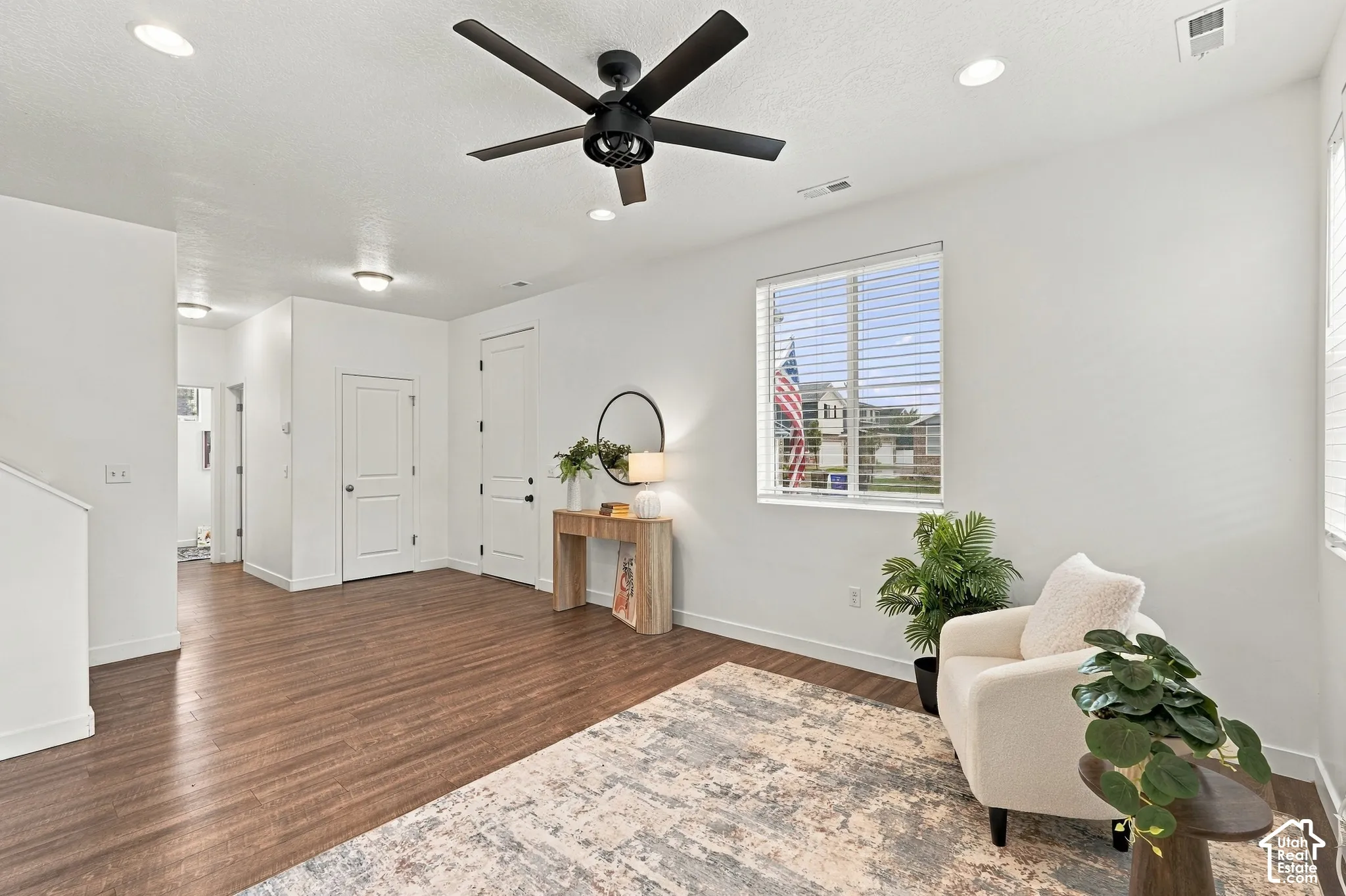 Recessed ceiling lighting, wood-finish flooring, white painted walls, and a black ceiling fan