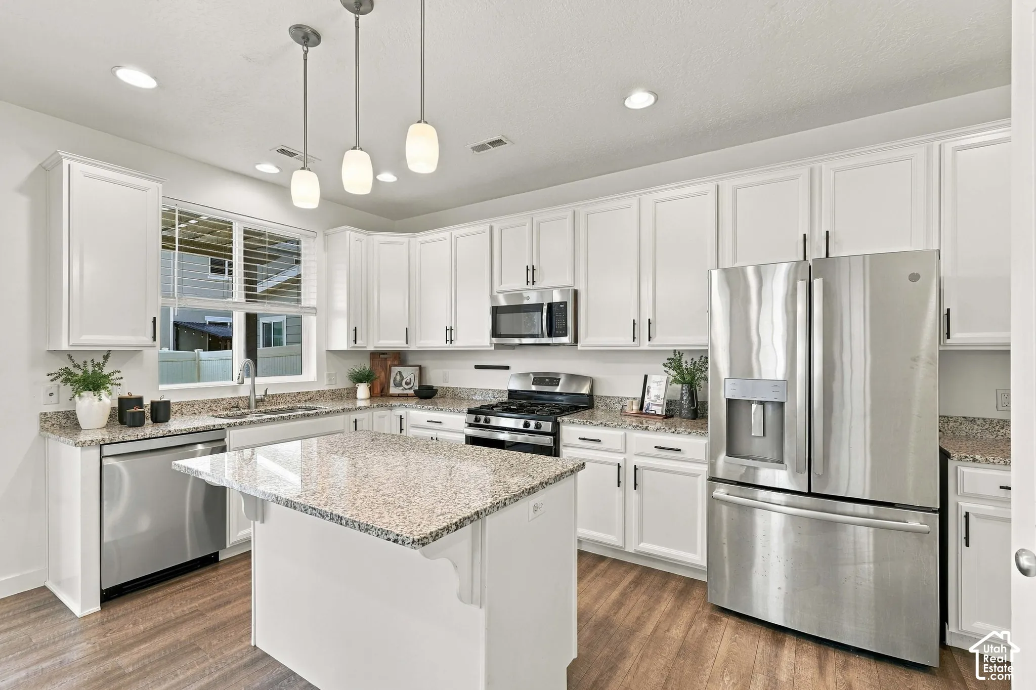 Kitchen featuring white cabinetry, stainless steel appliances, a center island with a granite-style countertop, recessed lighting, and wood-finish flooring