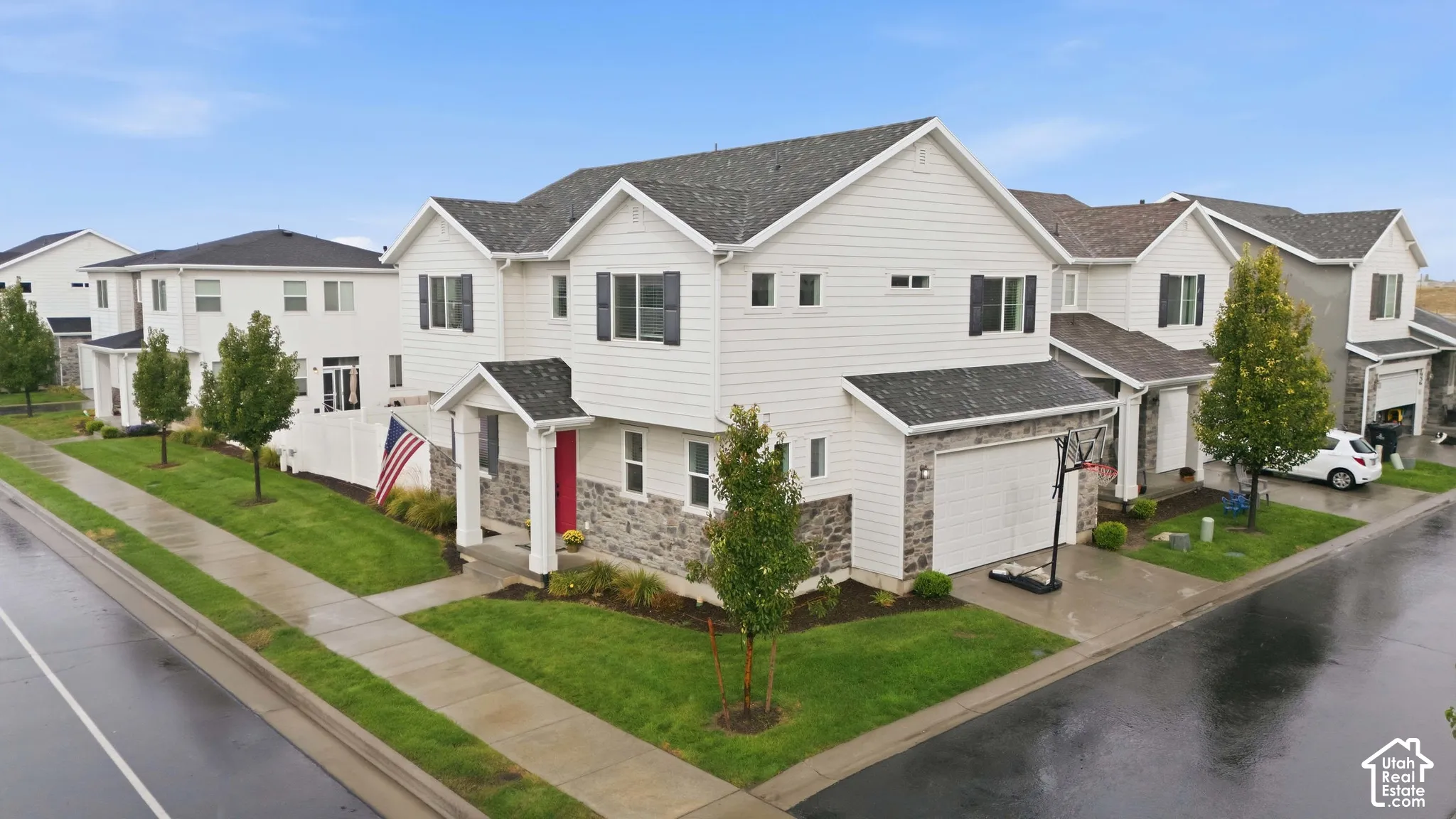 Two-story residence featuring white siding, a dark shingle roof, and a red entry door