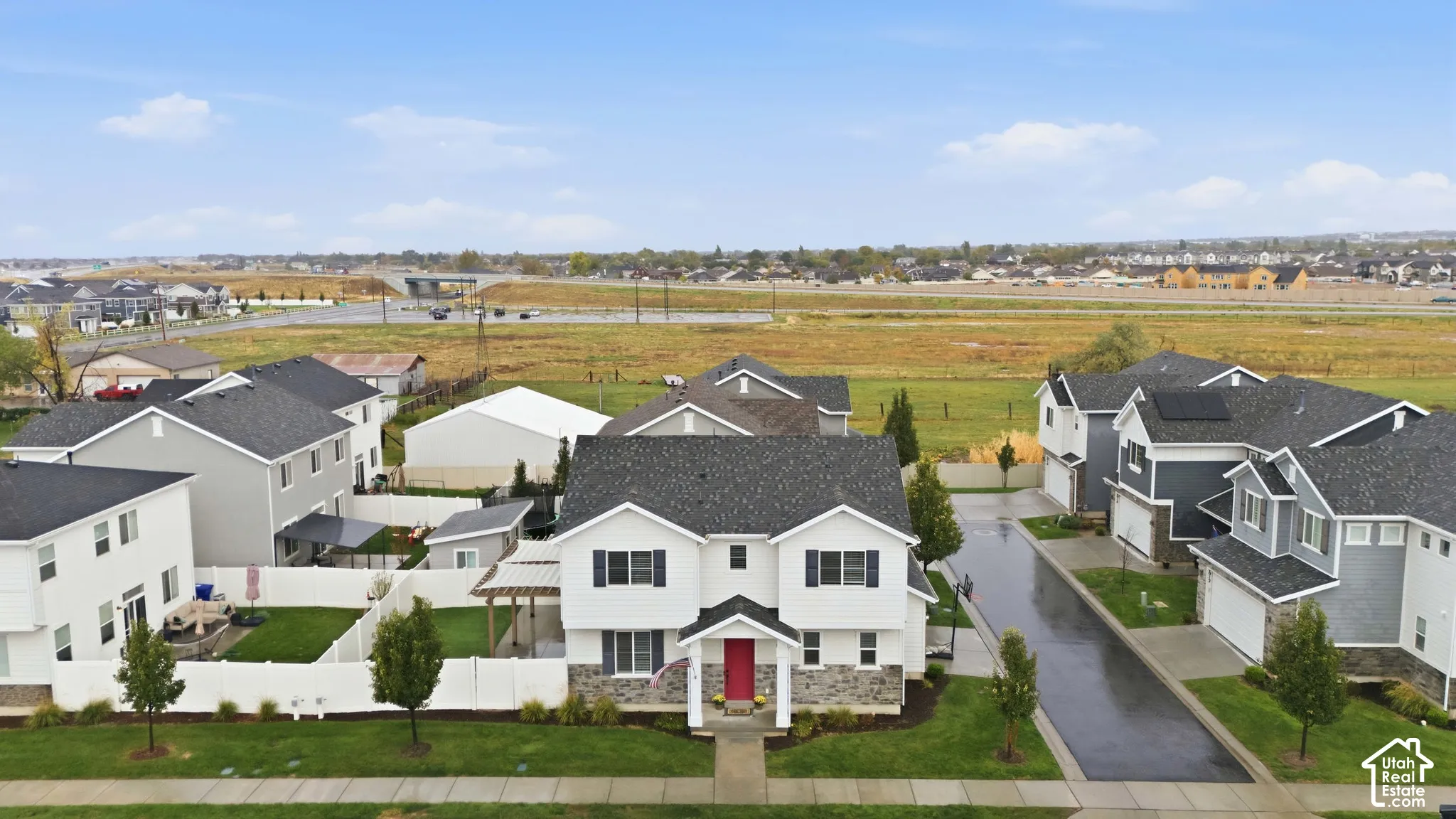 Two-story home with a dark gray shingle roof, white siding, stone veneer accents, and a red front door