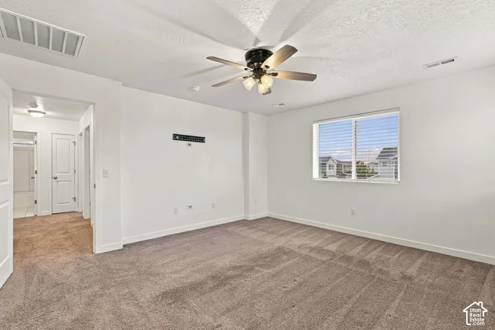 Carpeted room featuring a ceiling fan with integrated lighting, a window with blinds, and white painted walls