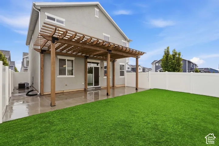 Expansive backyard with artificial turf, private vinyl fencing, a concrete patio, and a wood pergola