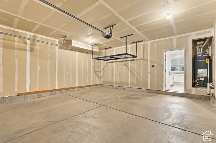 Concrete flooring, overhead storage racks, garage door opener mechanism, exposed ceiling joists, and a utility niche