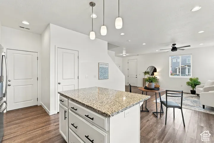 Kitchen island with a light granite countertop and pendant lighting