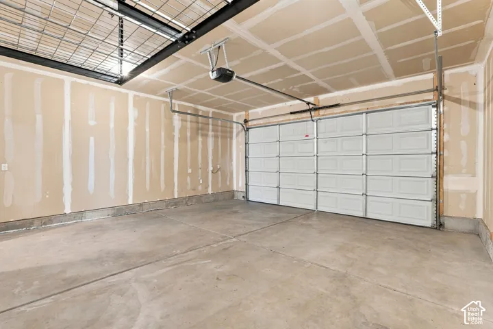 Spacious concrete floor garage featuring a paneled overhead door, an automatic garage door opener, and overhead wire storage shelving