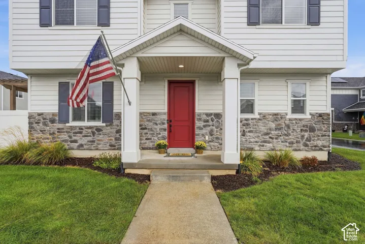 Welcoming entryway featuring a red door, covered porch, and stone-accented siding