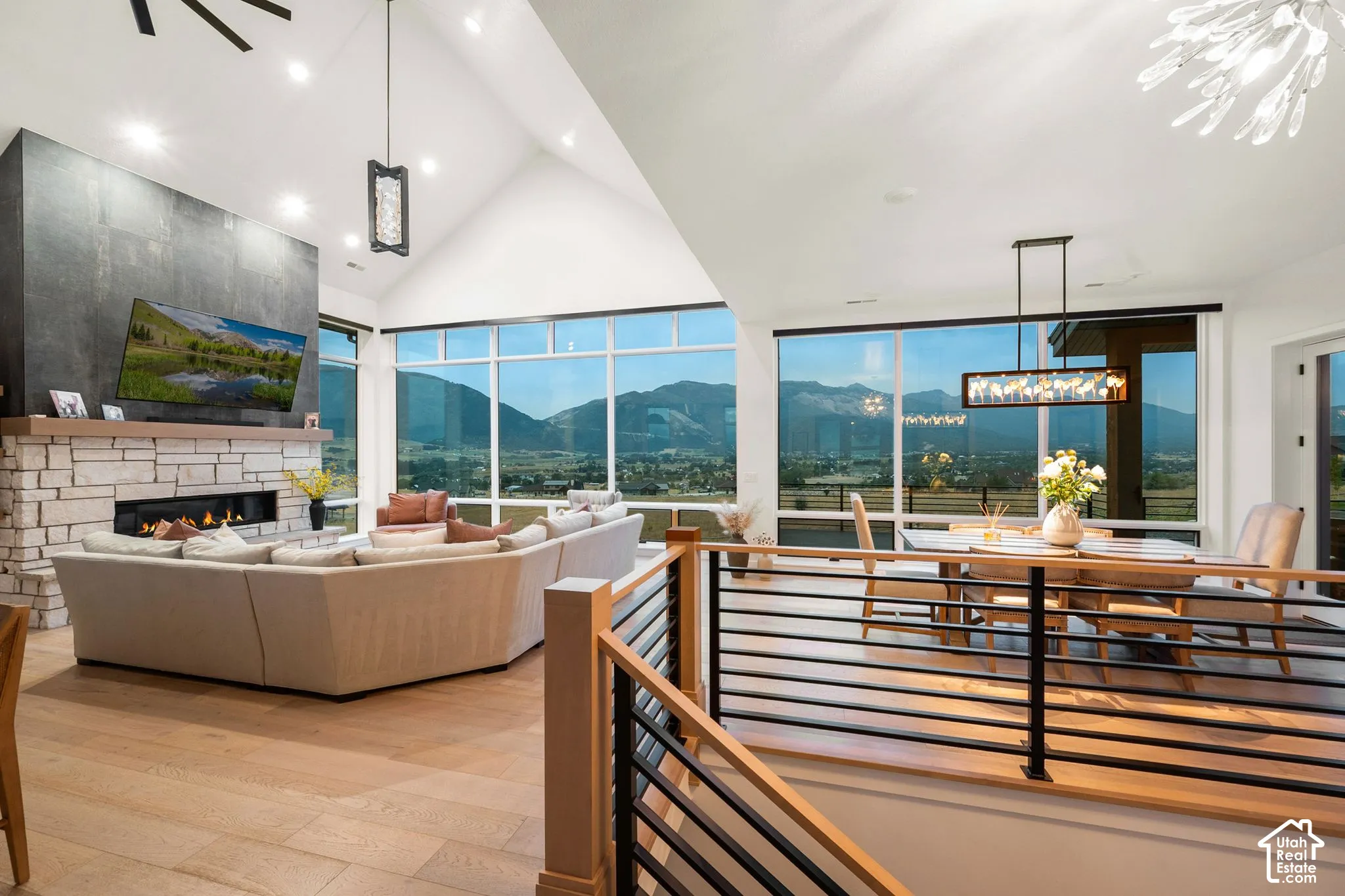Vaulted ceilings, a stone-clad fireplace, and expansive windows showcasing mountain scenery